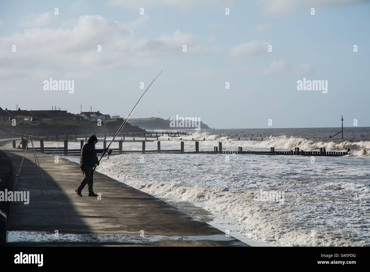 Un pescador de mar con su vara por la orilla. Foto de stock