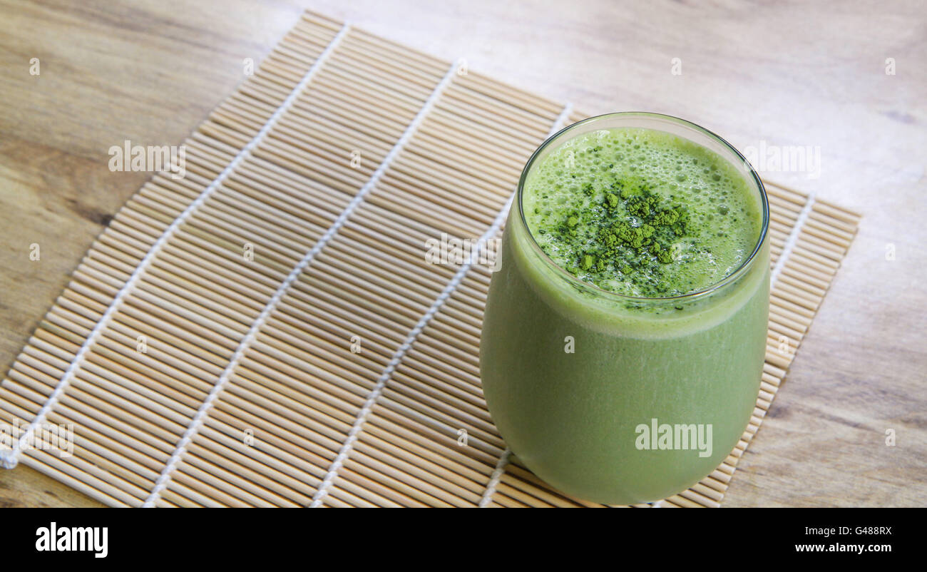 Batido de té verde matcha en cristal stemless de bambú Mat en la tabla de arriba el ángulo horizontal Foto de stock