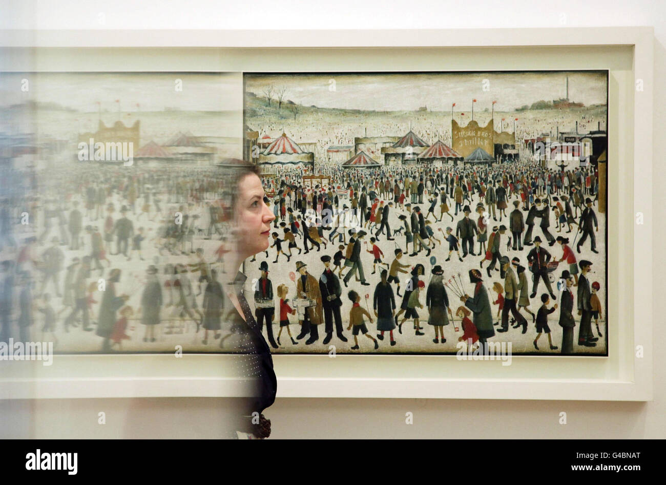 Elizabeth Flanagan, de la galería, estudia una pintura de LS Lowry, titulada 'Feria de Lancashire: El Viernes Santo, Daisy Nook', 1946, durante un avance de prensa de la Colección de Arte Gubernamental: En el trabajo, en la Galería Whitechapel, en el este de Londres. Por primera vez hoy se exhiben en una galería pública pinturas de la Colección de Arte del Gobierno. Foto de stock