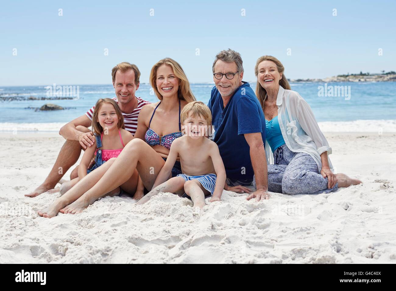 Modelo liberado. Tres generaciones de la familia sentado en la playa, retrato. Foto de stock