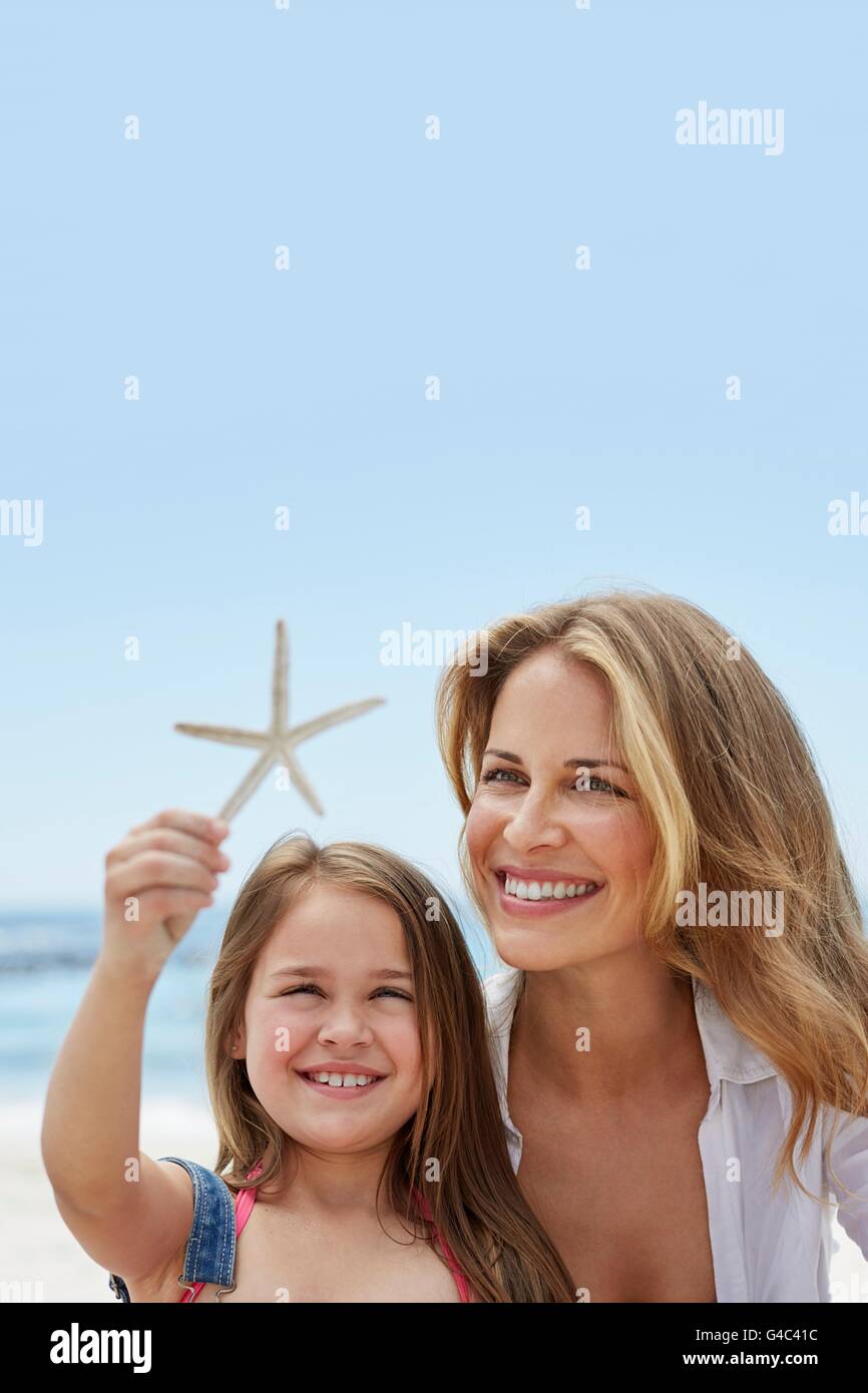 Modelo liberado. Madre con su hija en la playa con una estrella de mar. Foto de stock