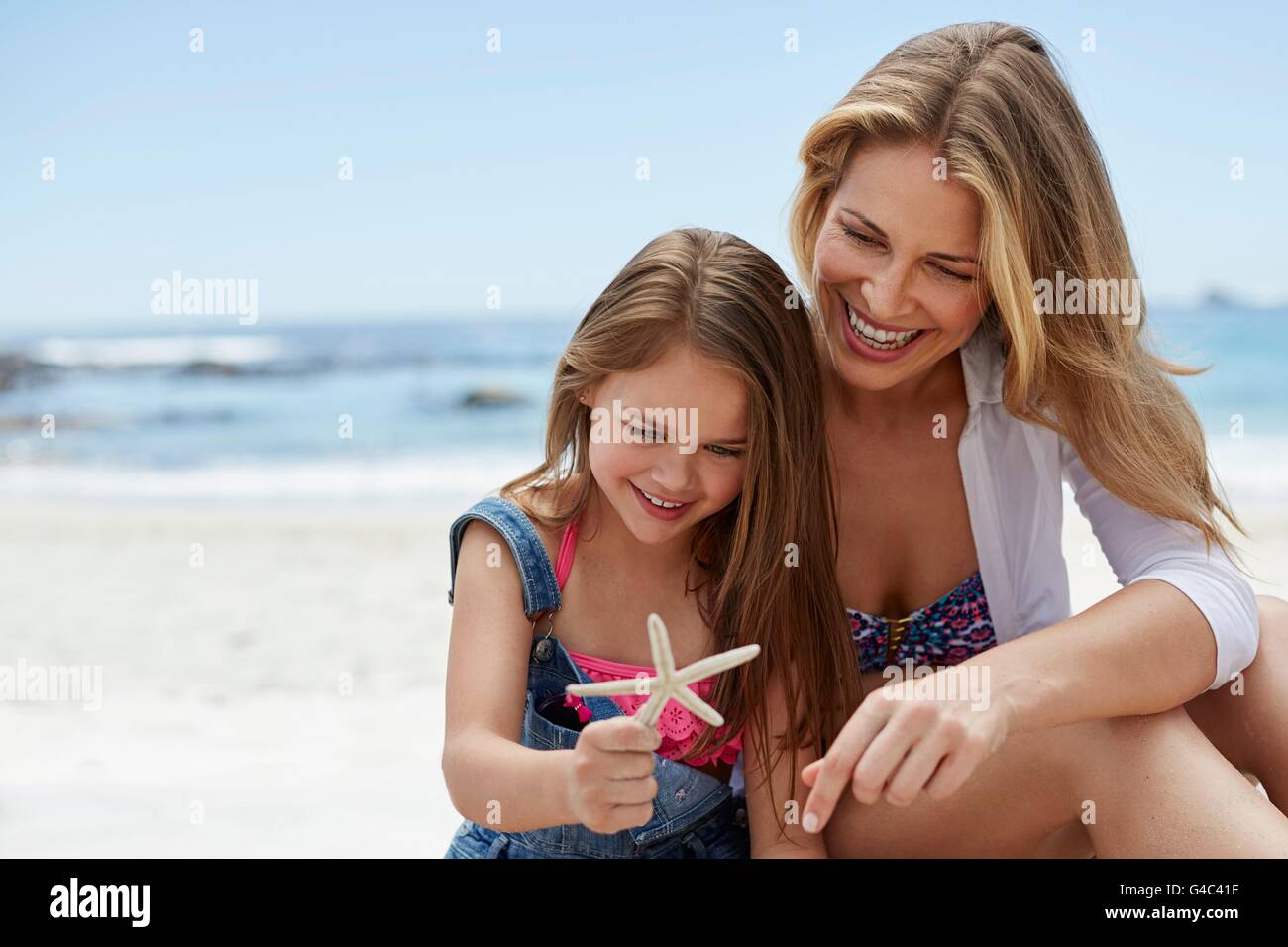Modelo liberado. Madre con su hija en la playa con una estrella de mar. Foto de stock