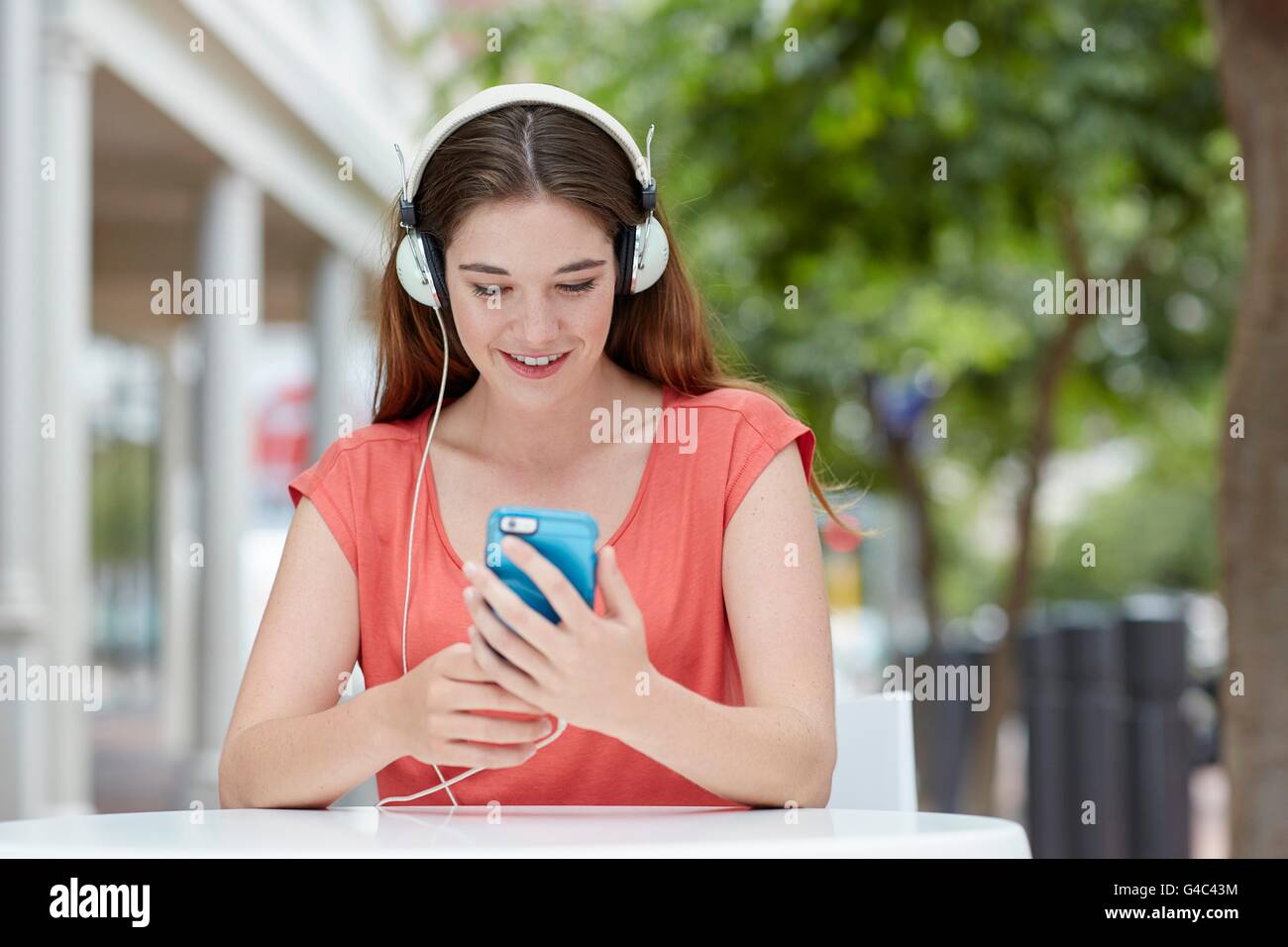 Modelo liberado. Mujer joven que lleva puestos los auriculares para escuchar música en el smartphone. Foto de stock