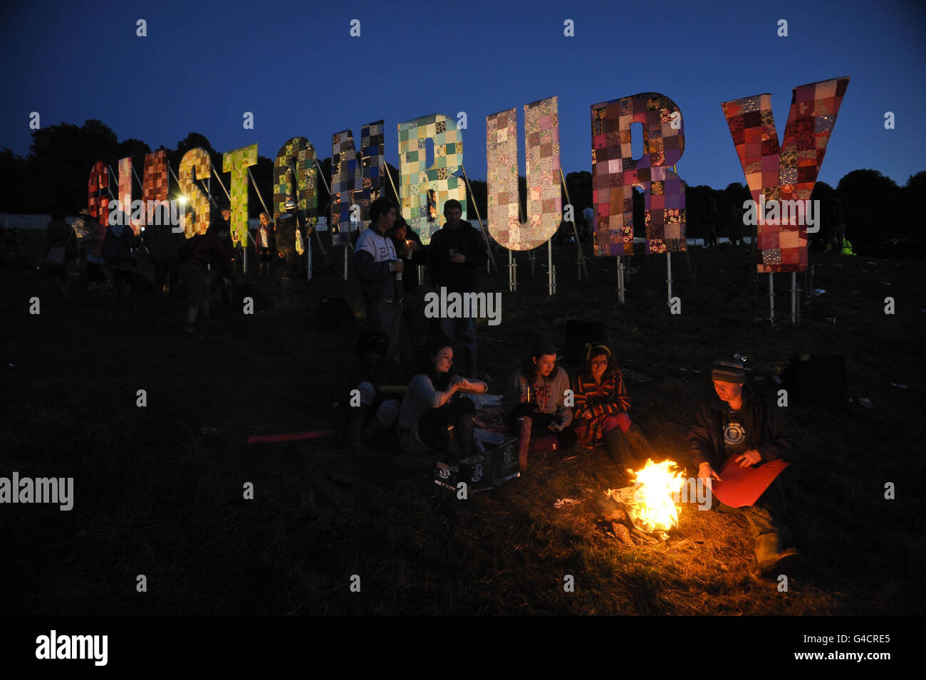 Los juerguistas encienden un fuego después de la puesta de sol cerca de la zona del parque en Glastonbury festival de música en la granja digna, Pilton. Foto de stock