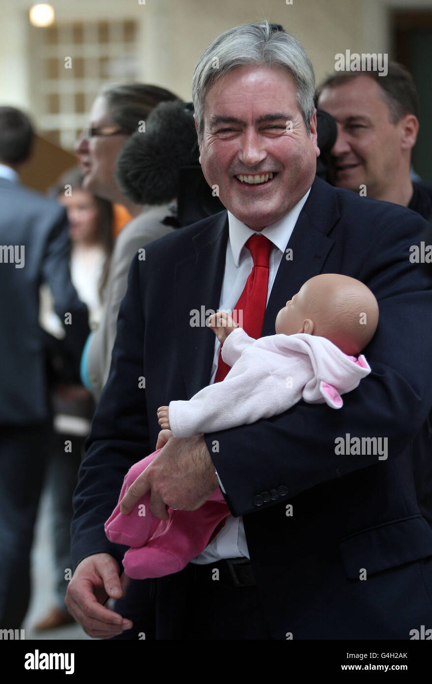 El líder del Partido Laborista Escocés, Iain Grey, tiene un bebé simulador en un intento de demostrar que llevar a un bebé al trabajo no es factible, en el Parlamento escocés de Edimburgo. Foto de stock