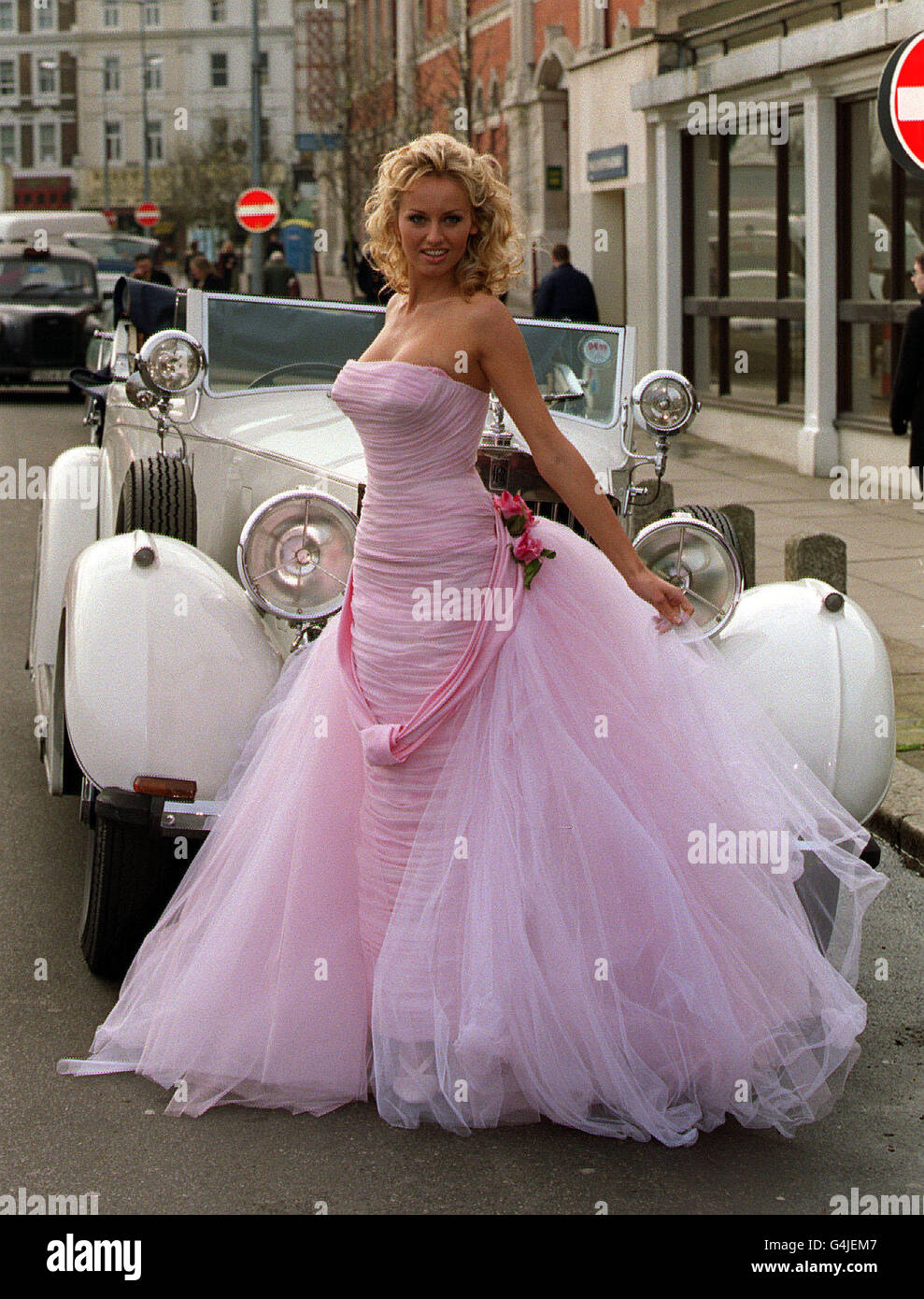 Adriana Sklenarikova, la cara de Wonderbra, con un vestido de boda rosa  delante de un coche antiguo en la apertura del National Wedding Show en el  Olympia Grand Hall, Londres Fotografía de