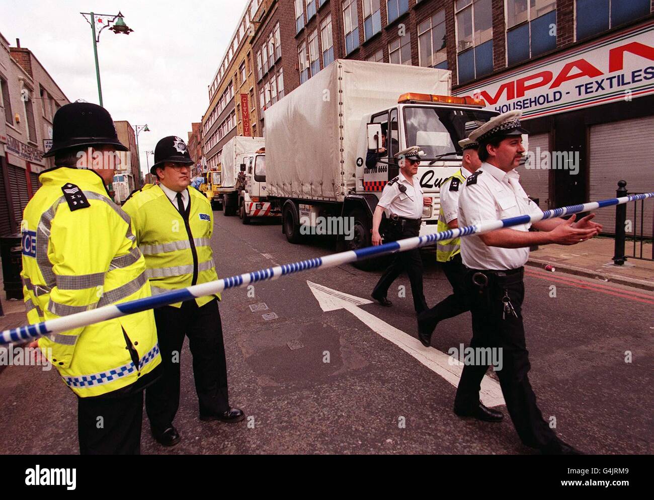 La policía levanta una barrera al final de Brick Lane, en Londres, para  permitir que los camiones transporten los restos cubiertos del vehículo en  el que detonó la bomba de clavos, y