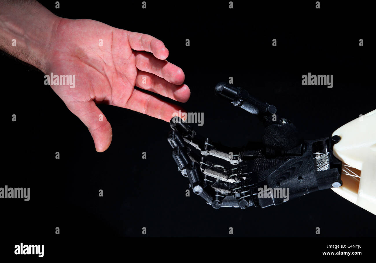 Una mano humana junto a Dexmart, una mano independiente robótica que ayuda a agarrar y manipular objetos de la misma manera que los humanos. El robot es uno de los más de 20 robots únicos, muchos de los cuales acaban de salir de laboratorios de investigación europeos y se muestran al público británico por primera vez en la exposición RobotvilleEU del Museo de la Ciencia. Foto de stock