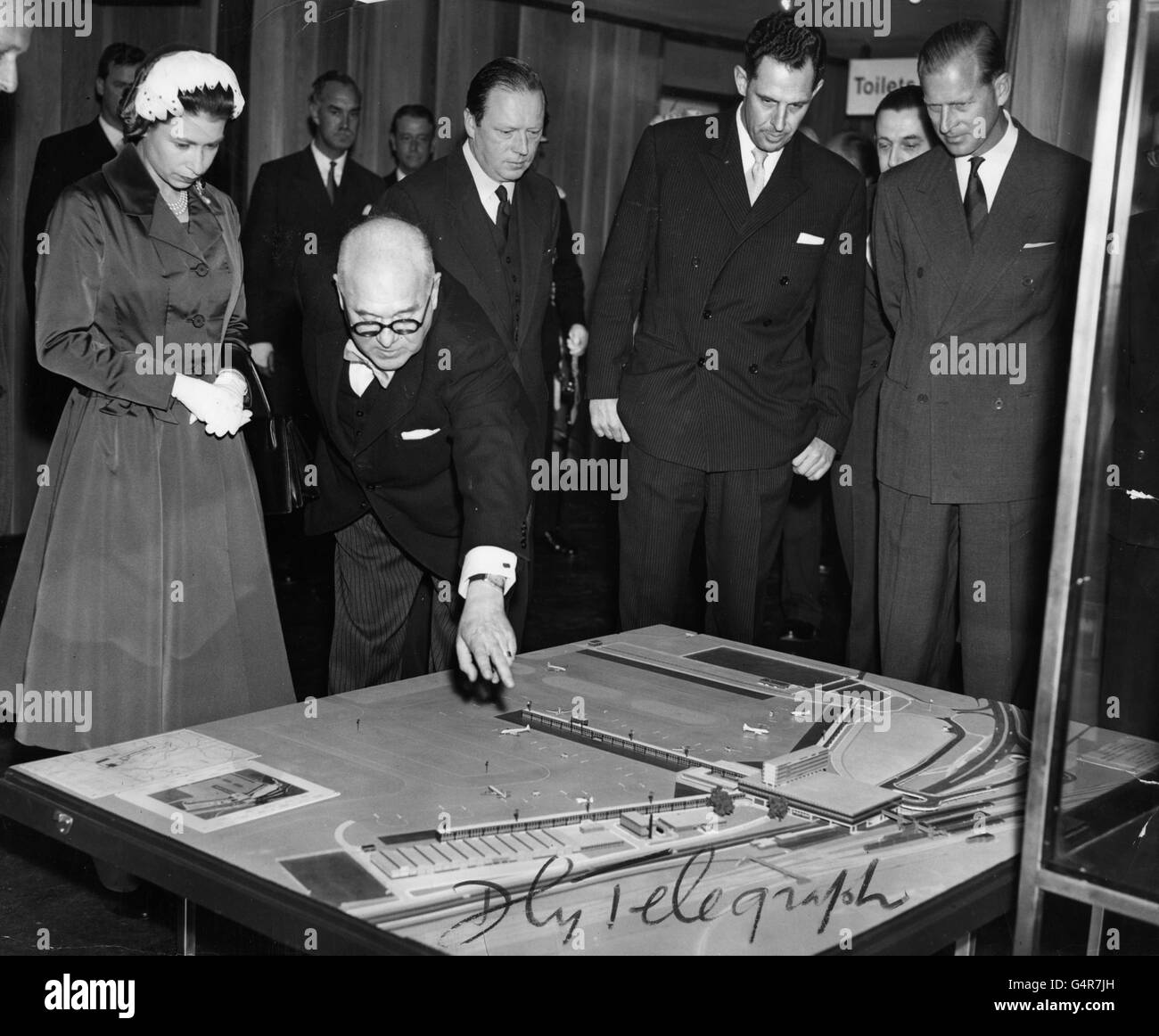 El ingeniero consultor Frederick S. Snow señala las características del nuevo aeropuerto de Gatwick en un modelo a la reina Isabel II y el duque de Edimburgo. Foto de stock