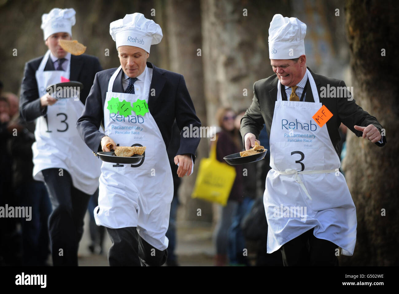 (Izquierda - derecha), Rob Hutton de Bloomberg Lord Listowel, y Stephen Lloyd MP participan en la anual Parliament Pancake Race en Westminster hoy, recaudando dinero para la organización benéfica Rehab. Foto de stock