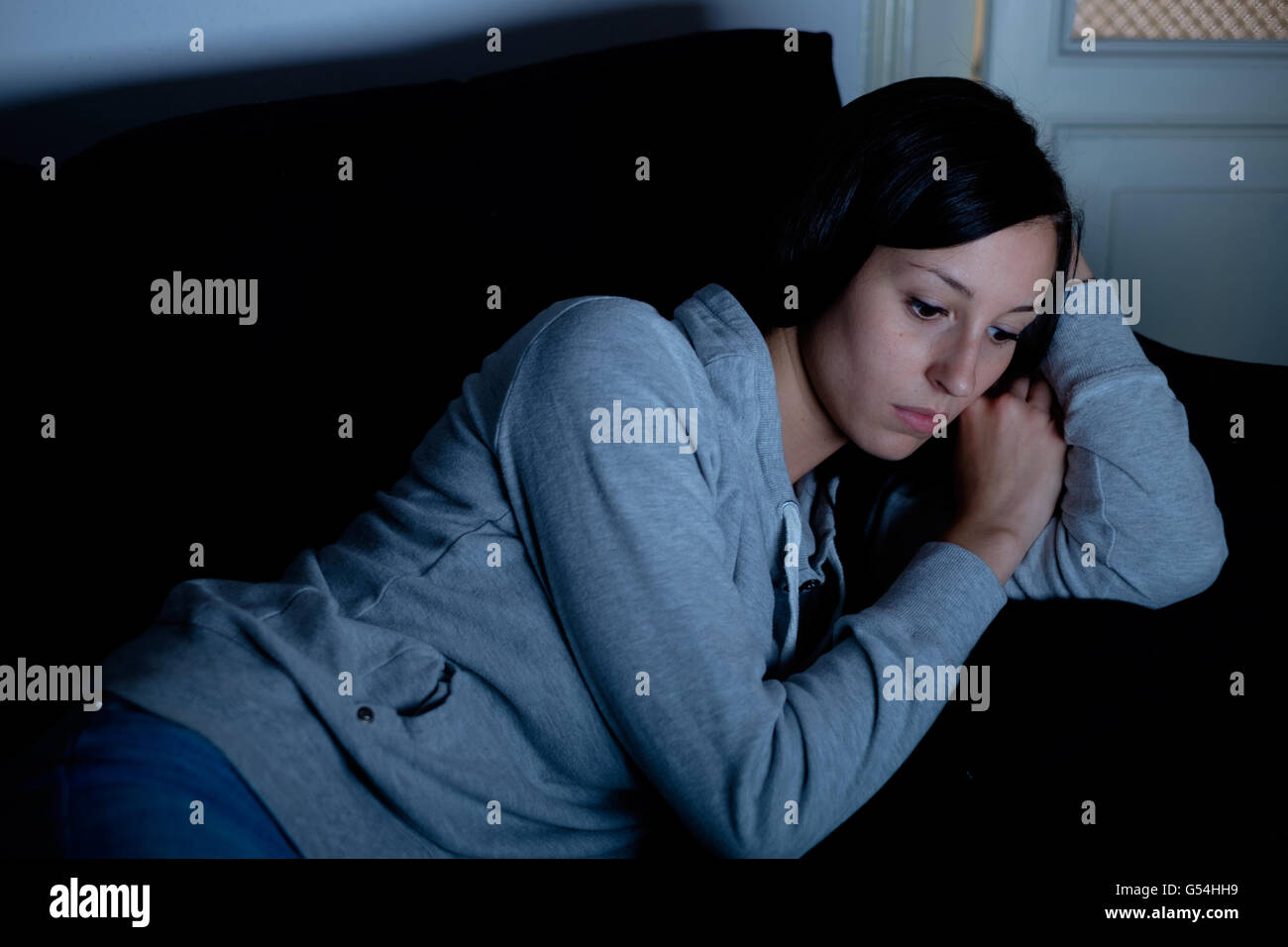 Triste deprimida mujer tumbado en la cama por la noche Foto de stock