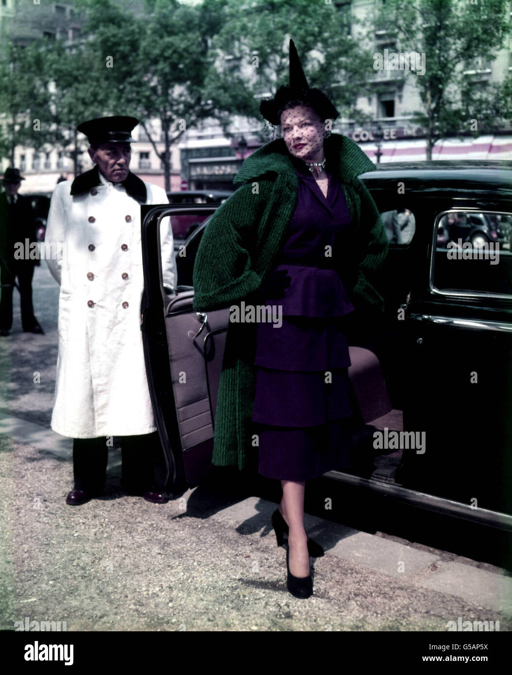 MODA DE LOS AÑOS CINCUENTA: 'Ceramique Chinoise', un modelo de lana para Carpentier. Se lleva una capa de lana azul/verde sobre un vestido violeta con una falda escalonada. París 1951. Foto de stock