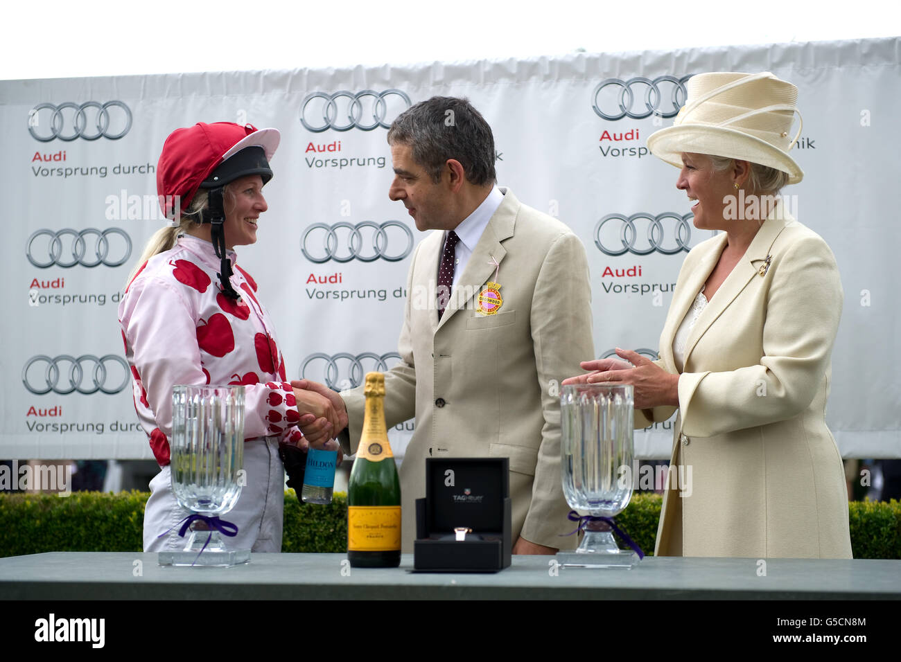 Rowan Atkinson (c) y Lady March (r) presentan a la diseñadora de joyas  Philippa Holland (l) con su premio después de montar a Russian Bullet a la  victoria en la Magnolia Cup