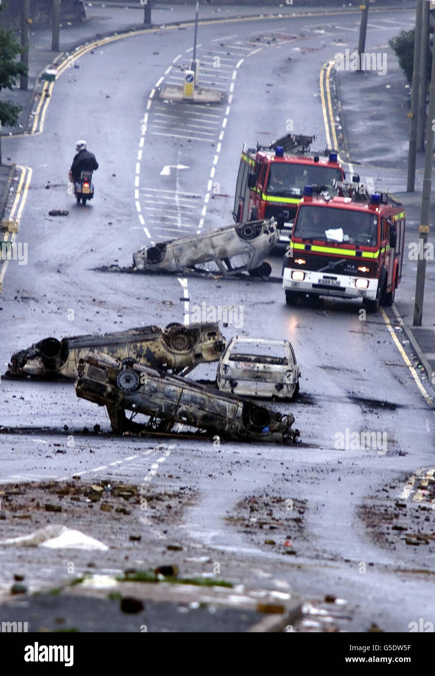 Dos motores de incendios pasaron coches quemados en la zona de Manningham en Bradford, después de la violencia de anoche en la ciudad que fue desencadenada por una manifestación de la Liga Anti Nazi contra el frente Nacional. Foto de stock