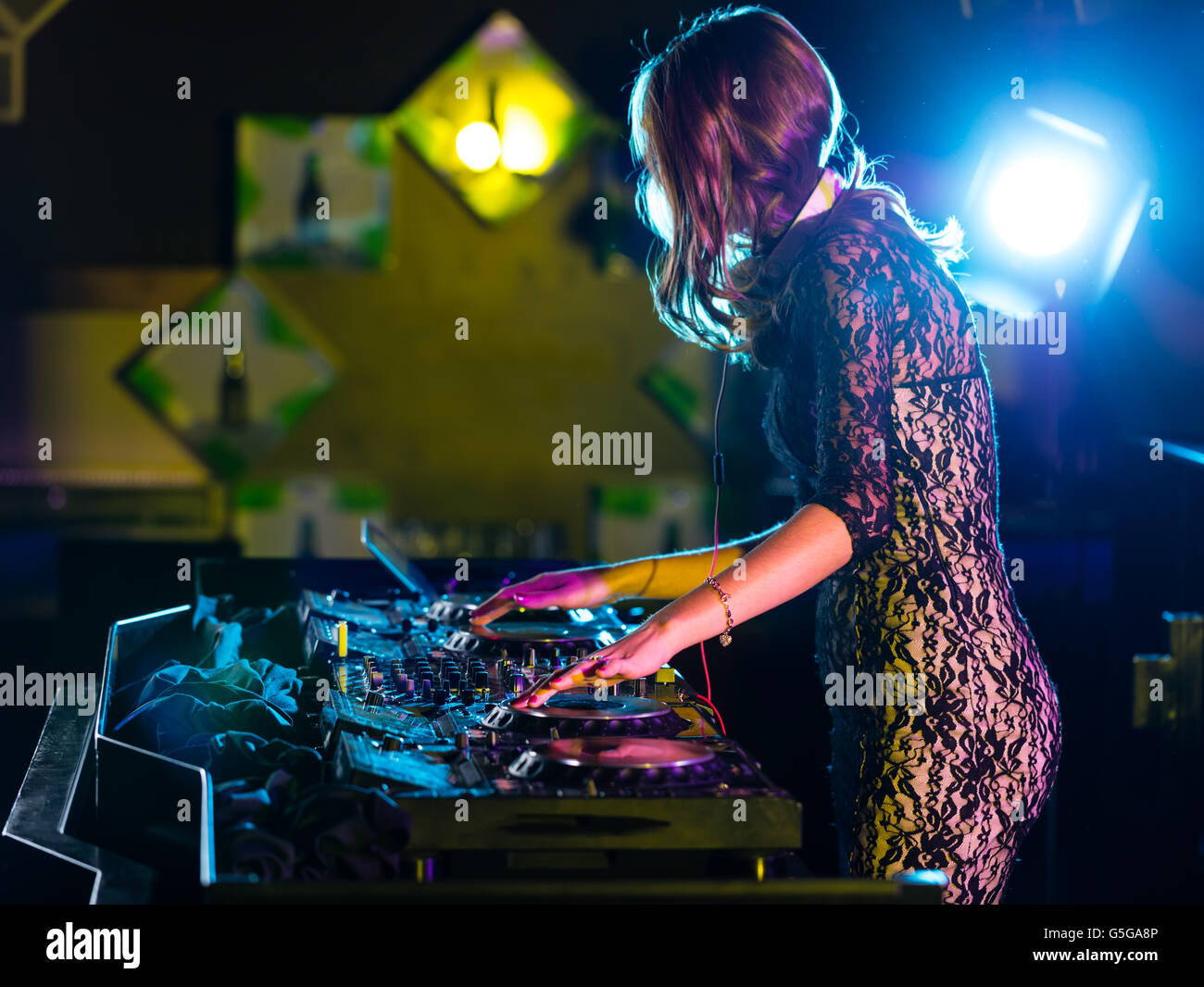 Disc Jockey niña morena mezclando música electrónica en el club Foto de stock