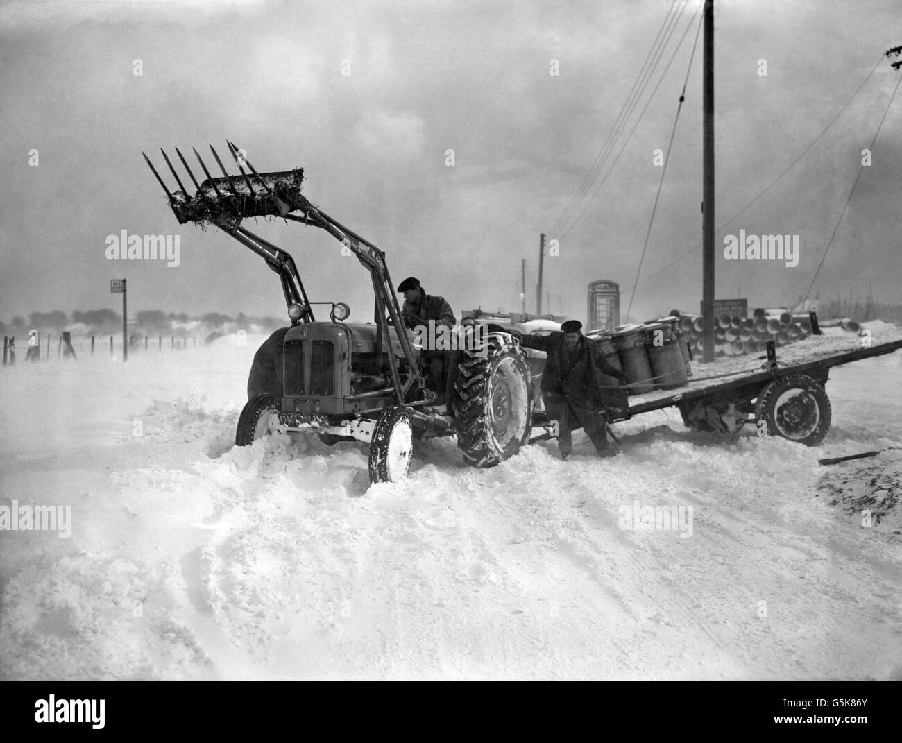 Un tractor ayuda a un vehículo de leche en la carretera Folkestone-Dover, que está bloqueado en algunos lugares por 6 pies de nieve gotea después de una fuerte ventisca. Foto de stock