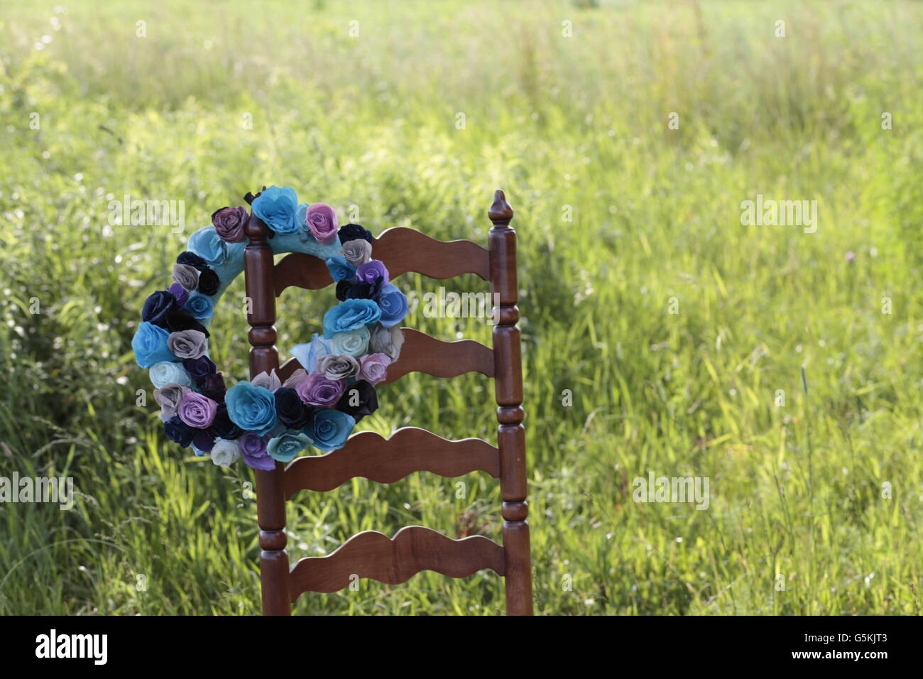 Hermosa flor azul ofrenda floral en campo verde en la escalera Silla respaldo Foto de stock