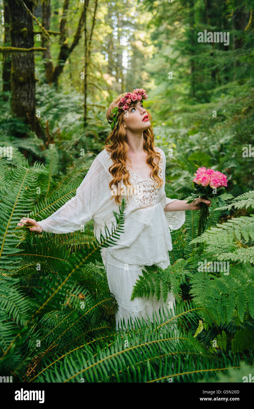 Mujer caucásica portando corona de flores en el bosque Foto de stock