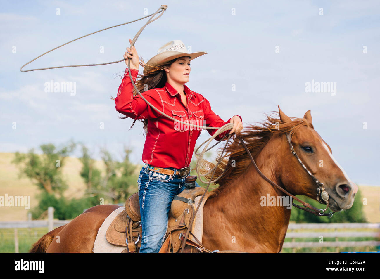 Cowgirl caucásica arrojando lasso a caballo Foto de stock