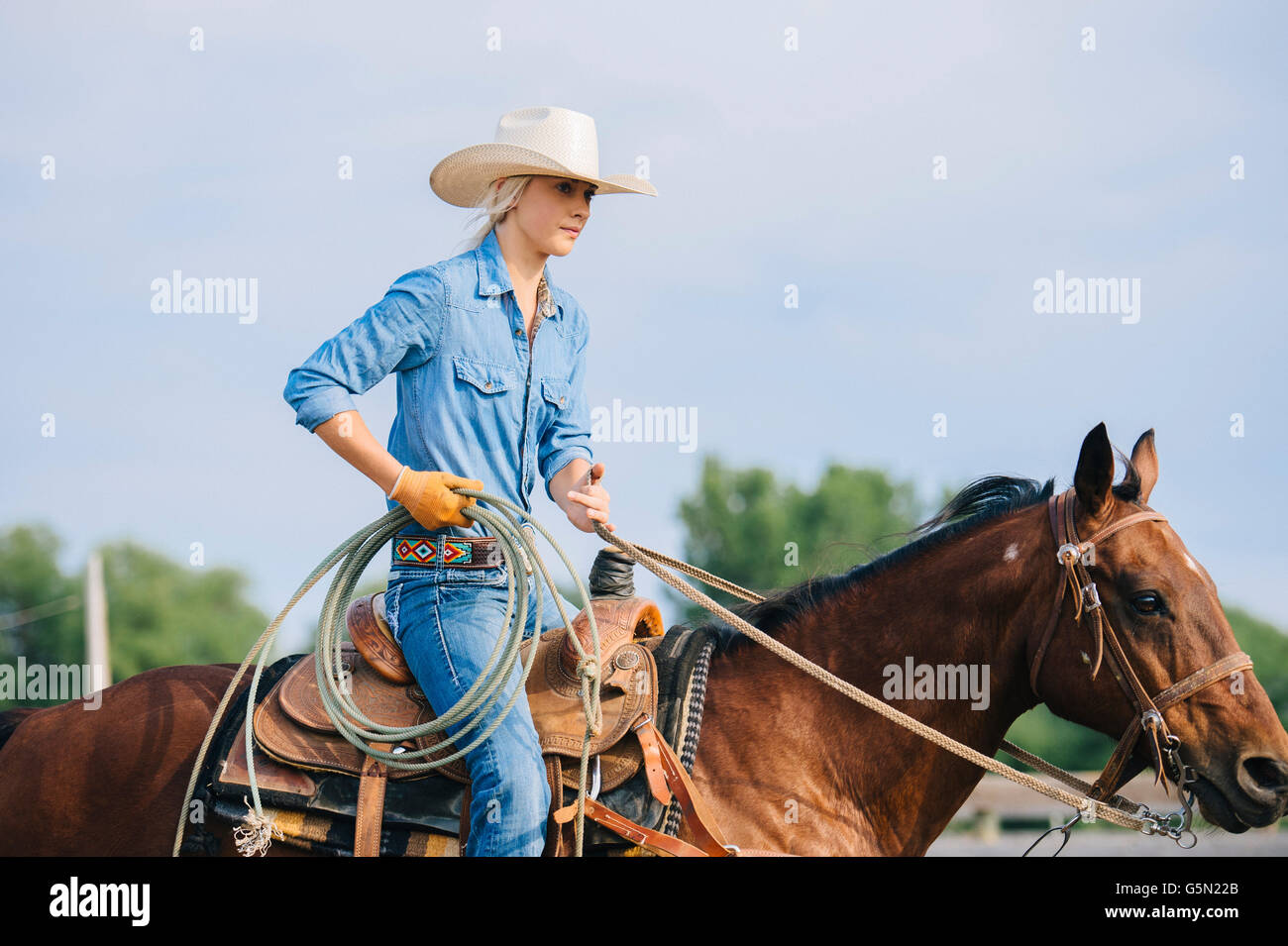 Cowgirl caucásica celebración lasso a caballo Foto de stock