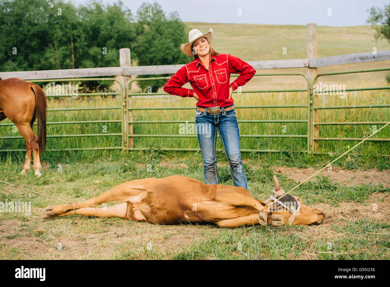 Cowgirl caucásica sonriendo con atado en rancho ganadero Foto de stock