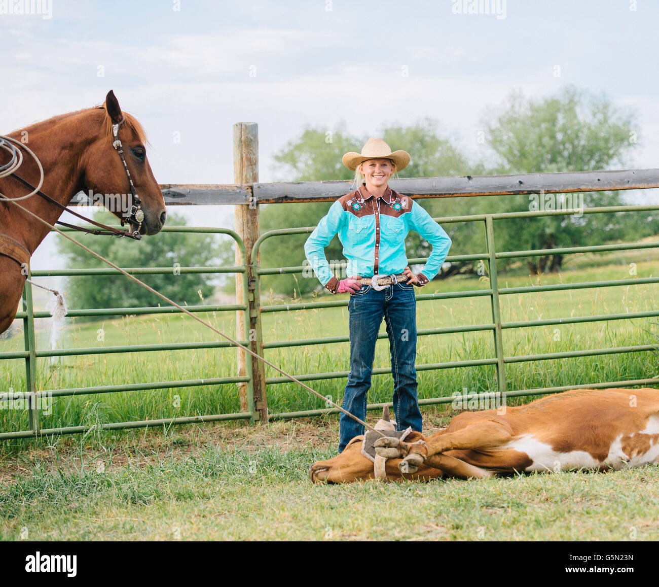Cowgirl sonriendo con atado en rancho ganadero Foto de stock