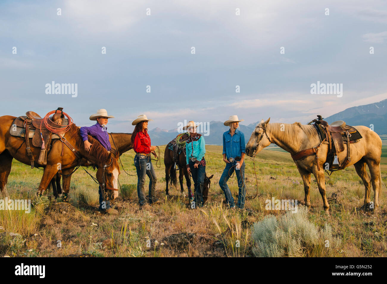 Vaqueros y vaqueras con caballos en el rancho Foto de stock
