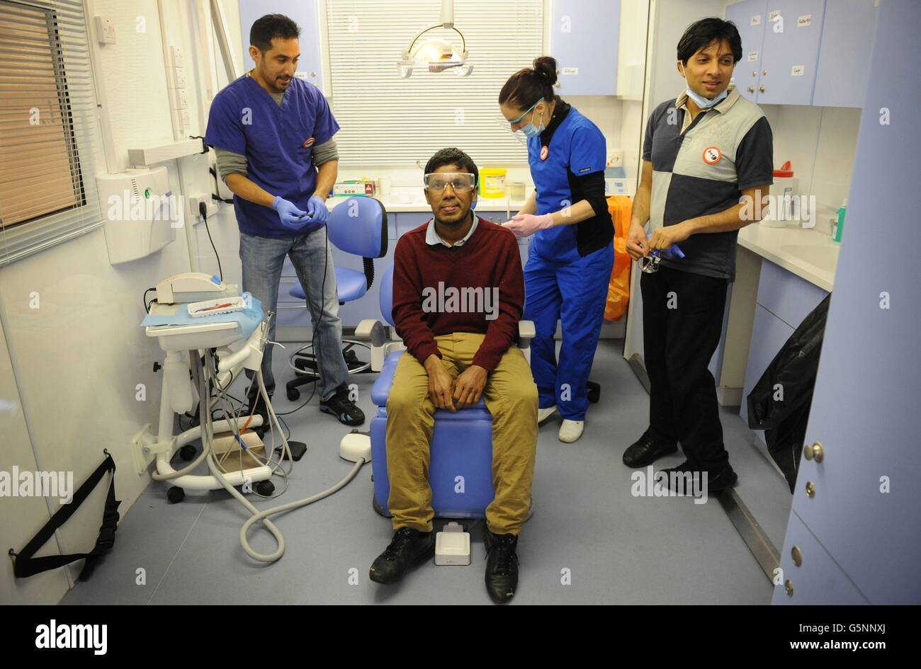 Un cliente llamado Raj tiene sus dientes revisados por un dentista en una cirugía móvil en la crisis de este año en el refugio de Navidad en los docklands de Londres, que junto con otros ocho refugios en la capital espera más de 3,000 invitados durante el período de Navidad. Foto de stock