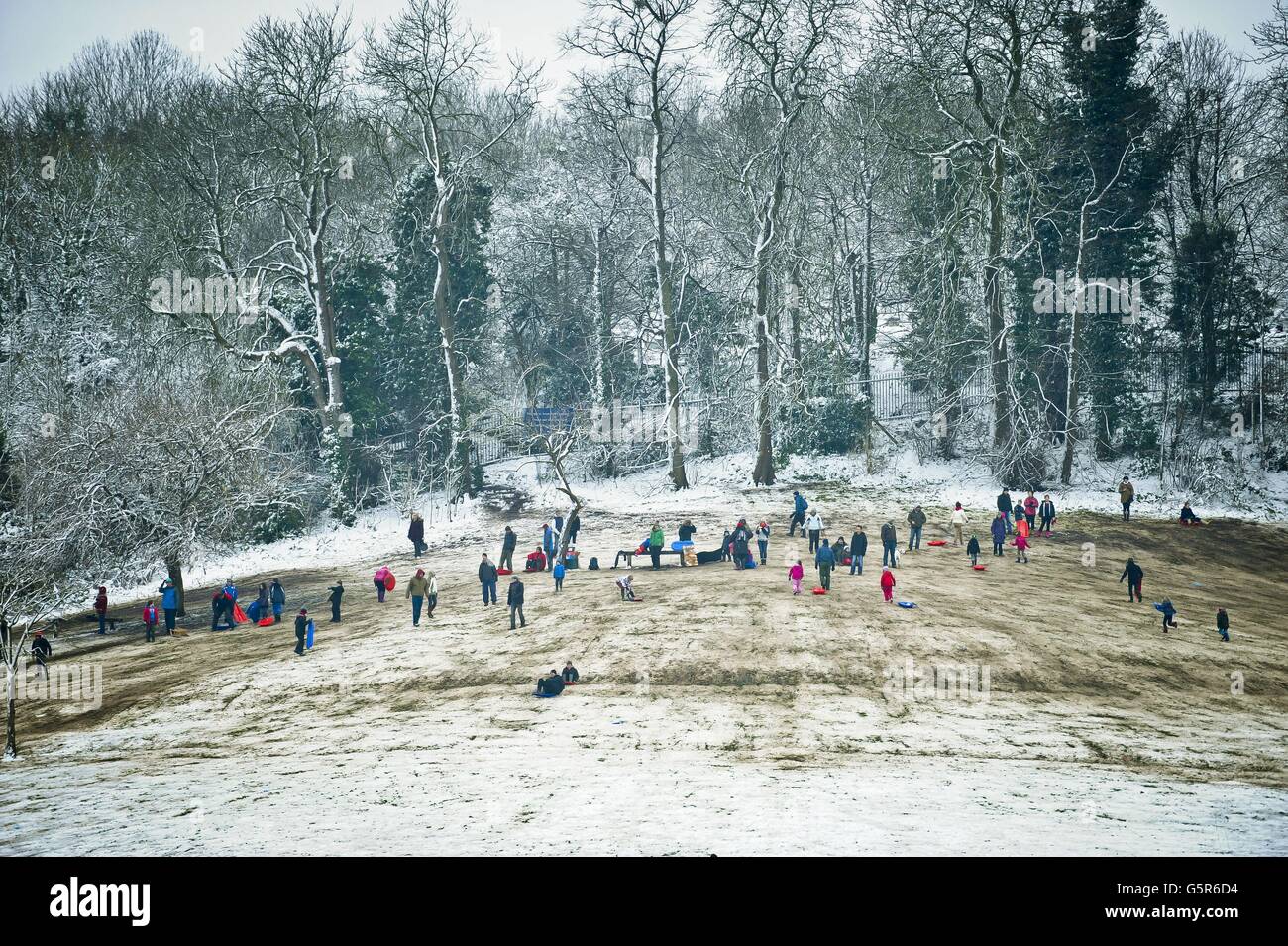 La nieve lentamente da paso al barro mientras la gente disfruta de trineos en Arnos Park, Brislington, Bristol, donde la nieve cayó antes del fin de semana y las temperaturas heladas han conservado la nieve. Foto de stock