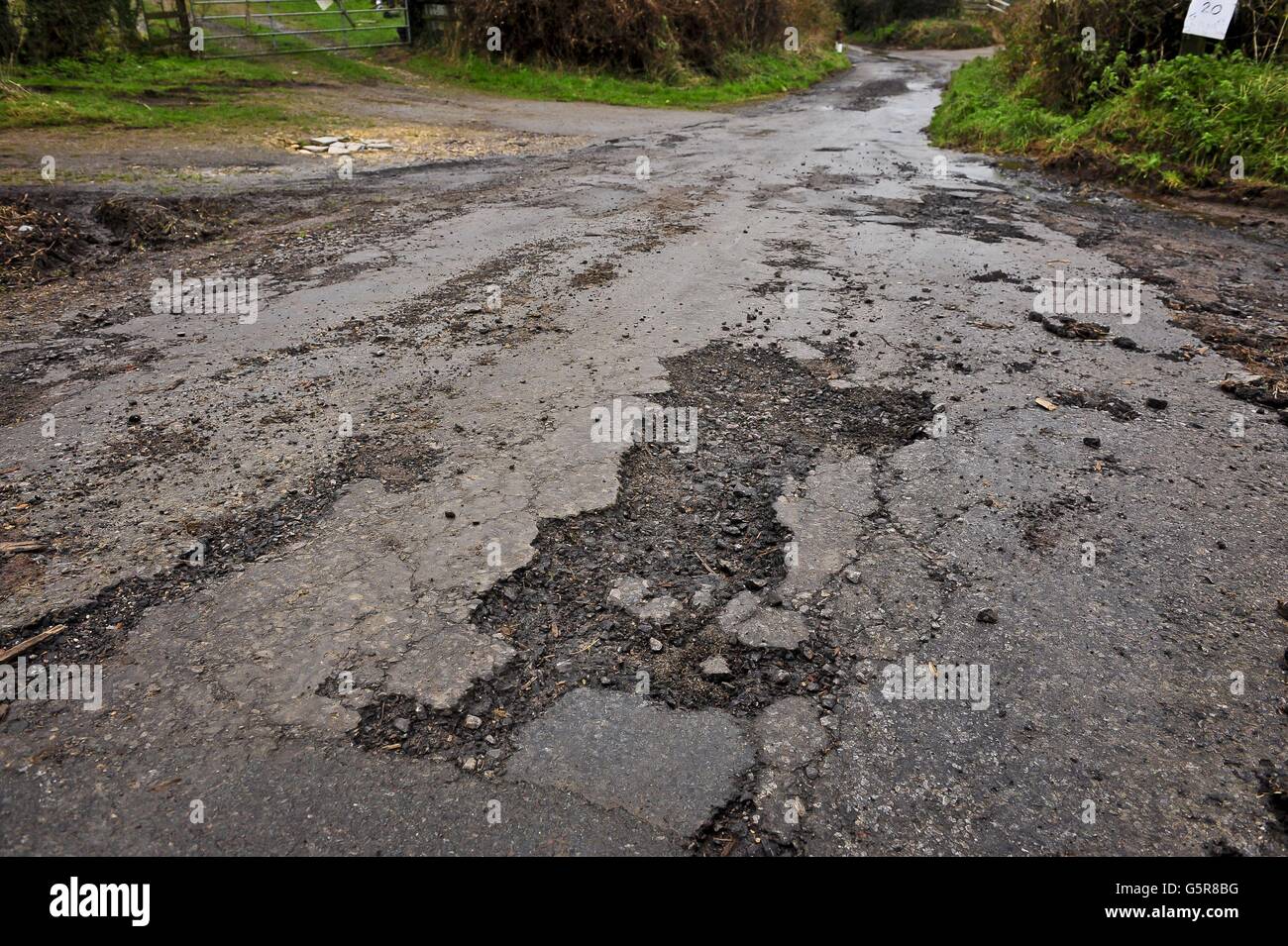Una superficie de carretera erosionada en una carretera de campo en Gloucestershire, ya que muchas carreteras en el suroeste necesitan reparaciones y trabajos de repavimentación después de un año de fuertes lluvias e inundaciones recientes, creando baches y escombros. Foto de stock