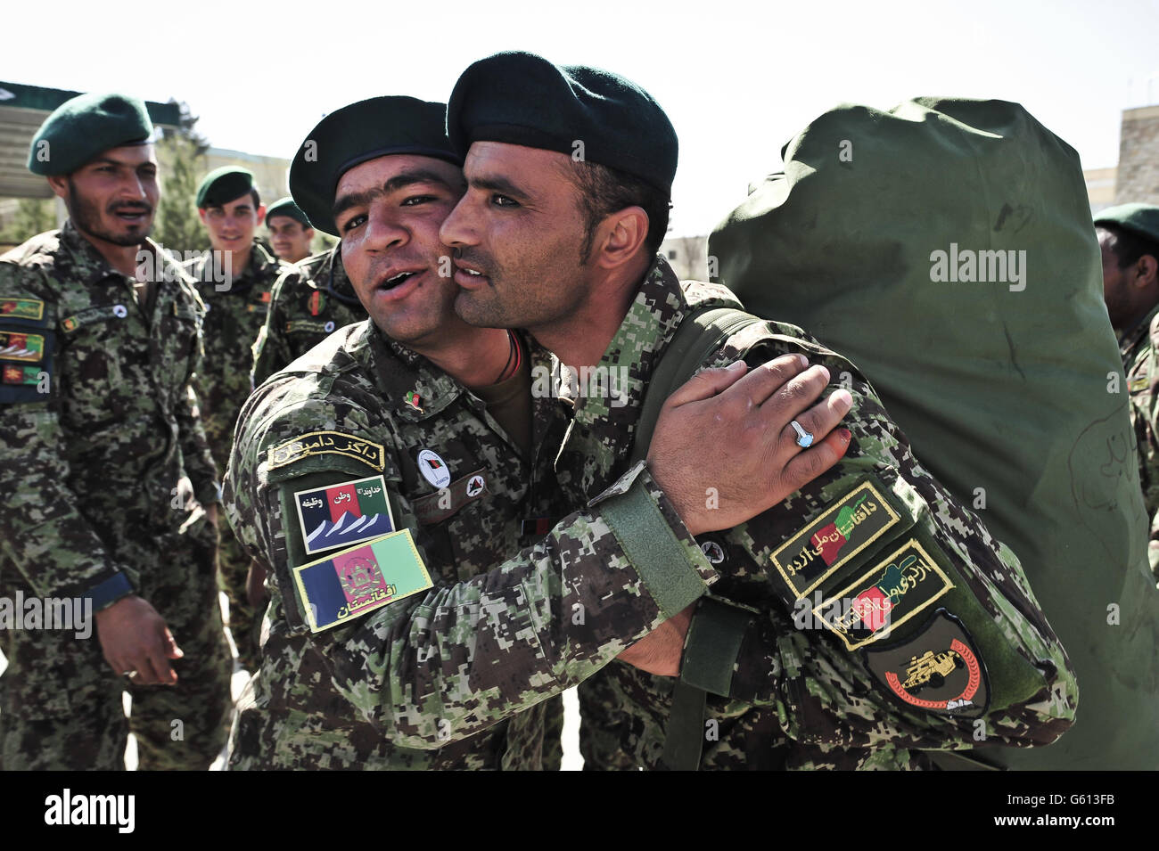 Oficiales no comisionados del Ejército Nacional afgano abrazan y dicen a Adiós en la plaza del desfile en el Centro de Entrenamiento Militar de Kabul, Kabul, Afganistán, después de ser asignado a una unidad de campo y finalmente se dirigían para ser desplegados en el teatro de operaciones para luchar contra los talibanes. Foto de stock