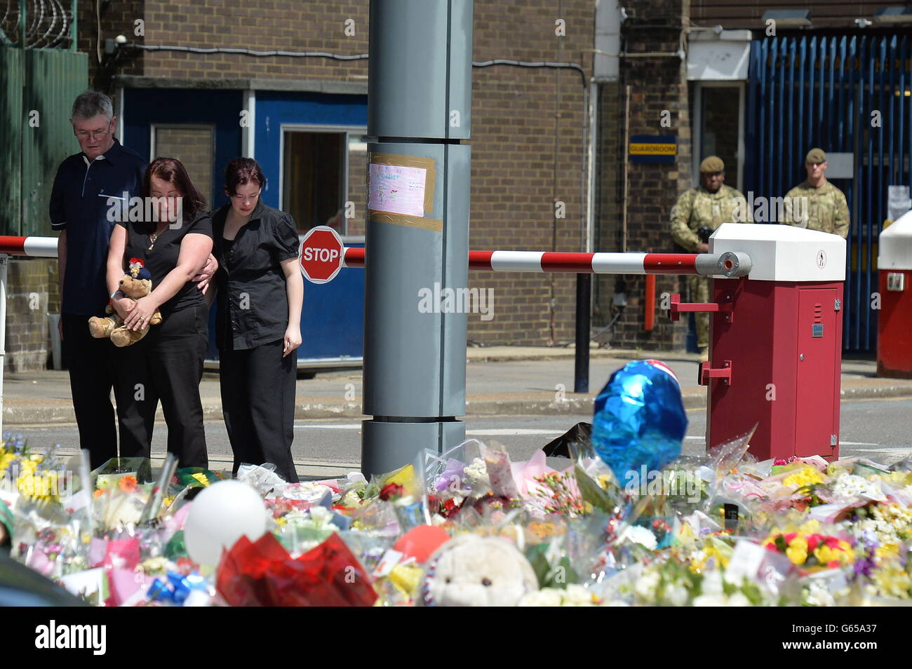 Lyn Rigby, madre de Drummer Lee Rigby, sosteniendo un oso de peluche se une a otros miembros de la familia mientras miran los tributos florales fuera de Woolwich Barracks mientras visitaban la escena de su asesinato en Woolwich, al sudeste de Londres. Foto de stock