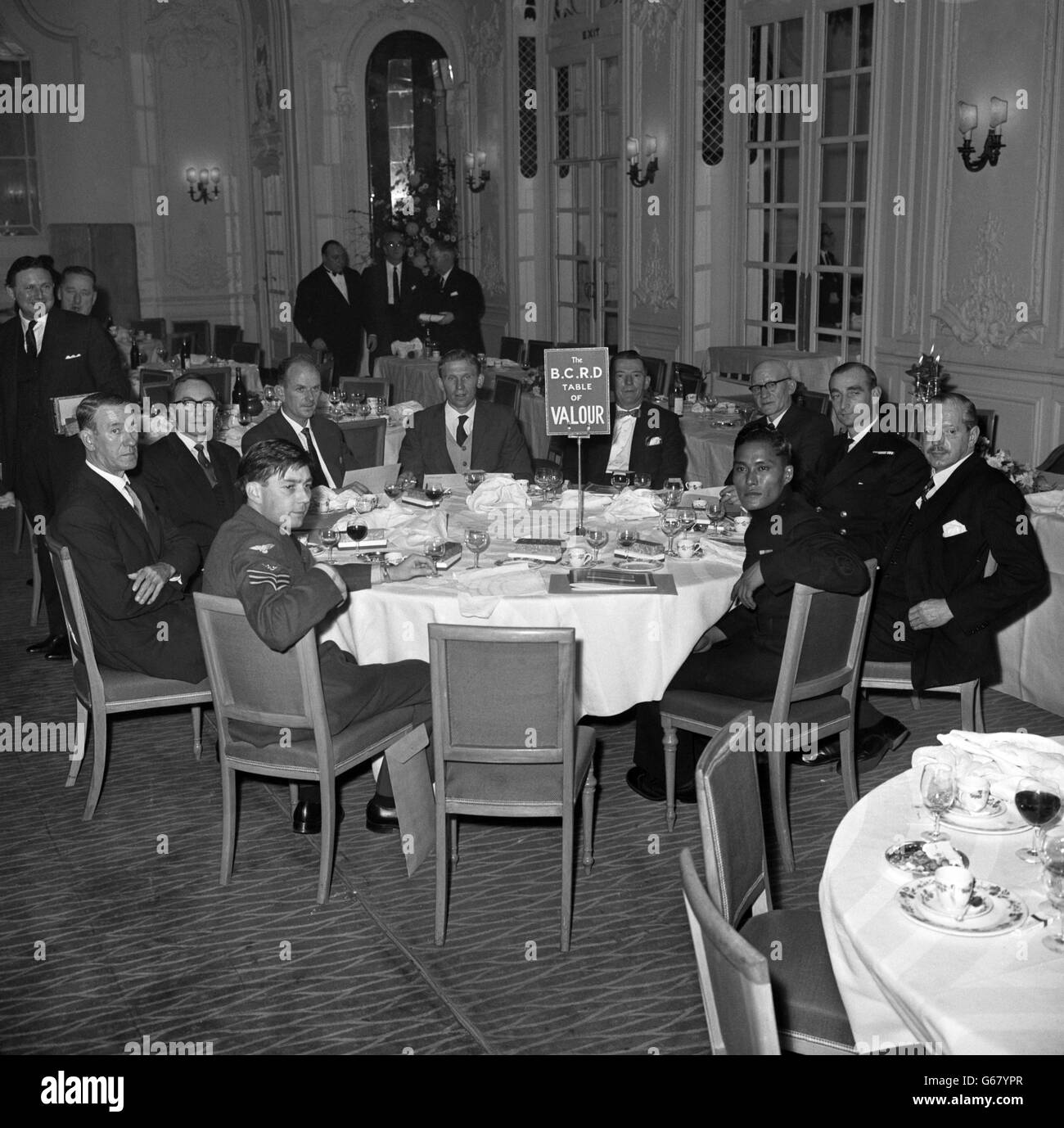 Diez hombres sentados alrededor de la Mesa de Valor poco antes de que otros huéspedes tomaran sus asientos en el Almuerzo Masculino del Año, celebrado en el Hotel Savoy, Londres. (Desde la izquierda) Sgt E.C. Smith, conductor británico de ferrocarriles Jack Mills, J. Laurence, P.M. Keenan, P. Darvill, A. Burrows, F. Frost, Teniente-Comandante E.R. Anson, capitán del grupo y Rifleman N. Rai. El almuerzo fue organizado por el Consejo Británico para la Rehabilitación de los Discapacitados y el tema fue 'Valor y Logro'. Foto de stock