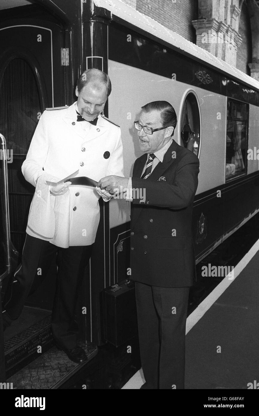 El periodista de viajes Alan Whicker revisa su billete con un portero antes de subir al Venice-Simplon Orient Express, que sale de Victoria Station, Londres, para su viaje inaugural. La sección británica del viaje a Folkestone está en todos los vagones Pullman veteranos restaurados a condiciones prístinas. Foto de stock