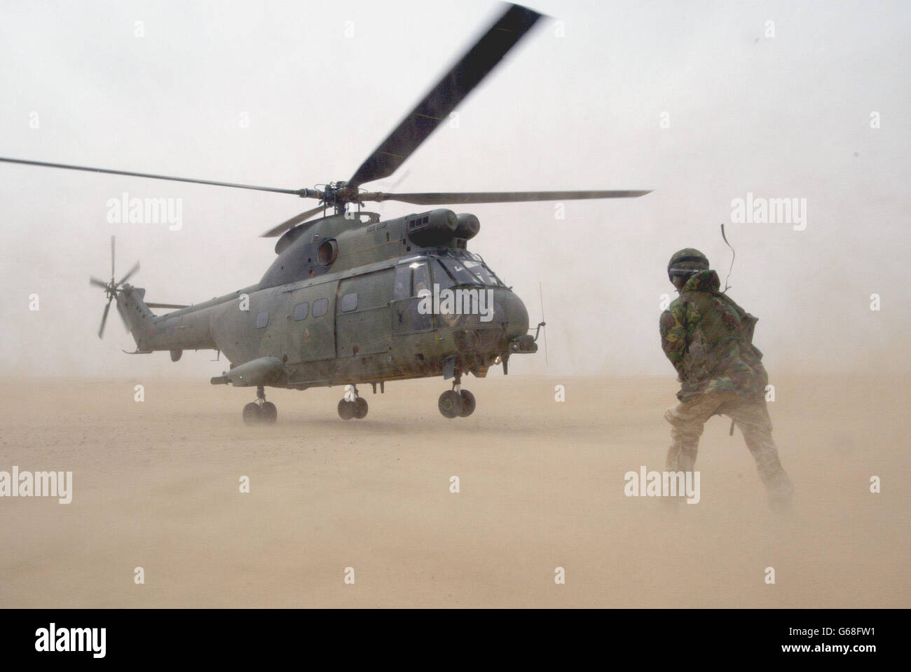 Un Puma británico de la Fuerza Aérea Real, una fuerza conjunta de helicópteros, se prepara para despegar mientras un maestro de carga observa durante un diseño de operación de asalto aéreo de práctica para capturar aeródromos enemigos, en el desierto fuera de la ciudad de Kuwait. Foto de stock