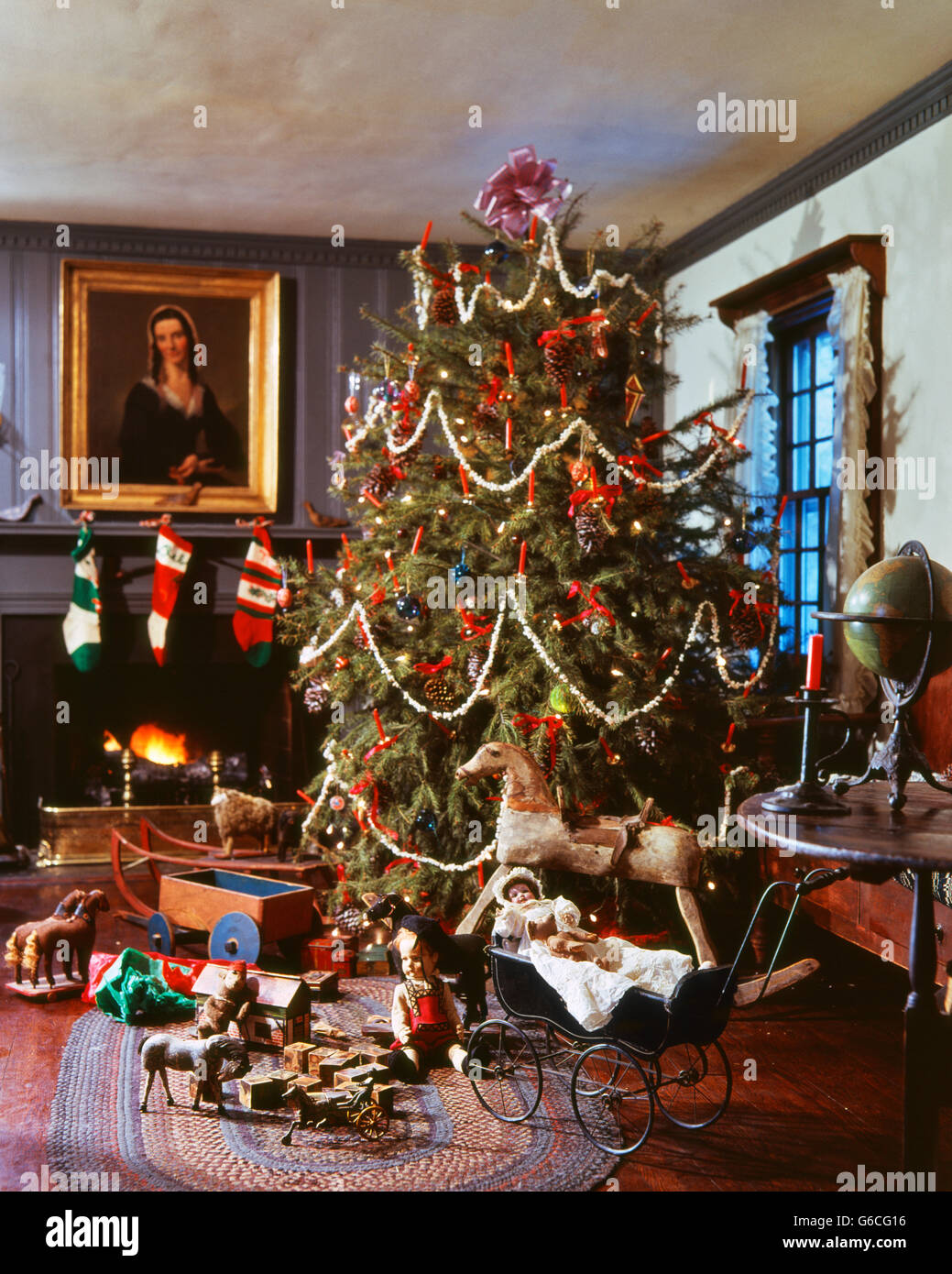 1970 1980 viejo árbol de navidad decorado con guirnaldas de palomitas de maíz por chimenea juguetes antiguos alrededor Foto de stock