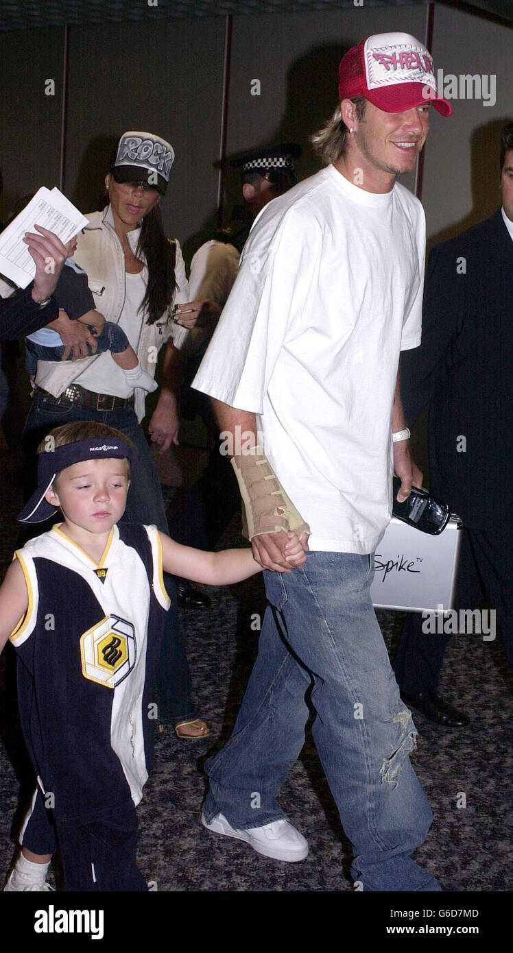 El futbolista David Beckham con su hijo Brooklyn es seguido por su esposa Victoria (izquierda) y su bebé familia Romeo cuando llegan al aeropuerto de Heathrow. Foto de stock