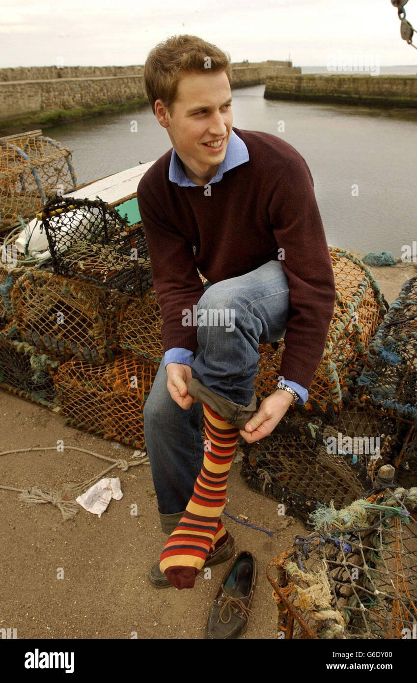 El Príncipe Guillermo reemplaza sus zapatos y calcetines después de correr  por el mar en la playa de St Andrews.The Prince es dos años en un título de  Historia del Arte de