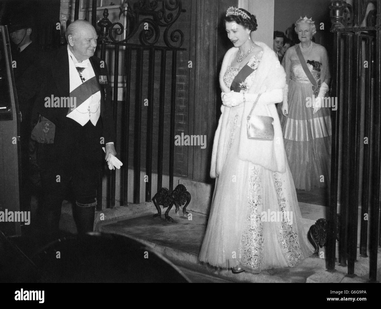 Con su banda como Caballero del Garter, Sir Winston Churchill abre la puerta del coche de la Reina Isabel, cuando se va después de cenar con él y con el Duque de Edimburgo y otros distinguidos invitados. Mirando la puerta está su anfitriona, Lady Churchill. Foto de stock