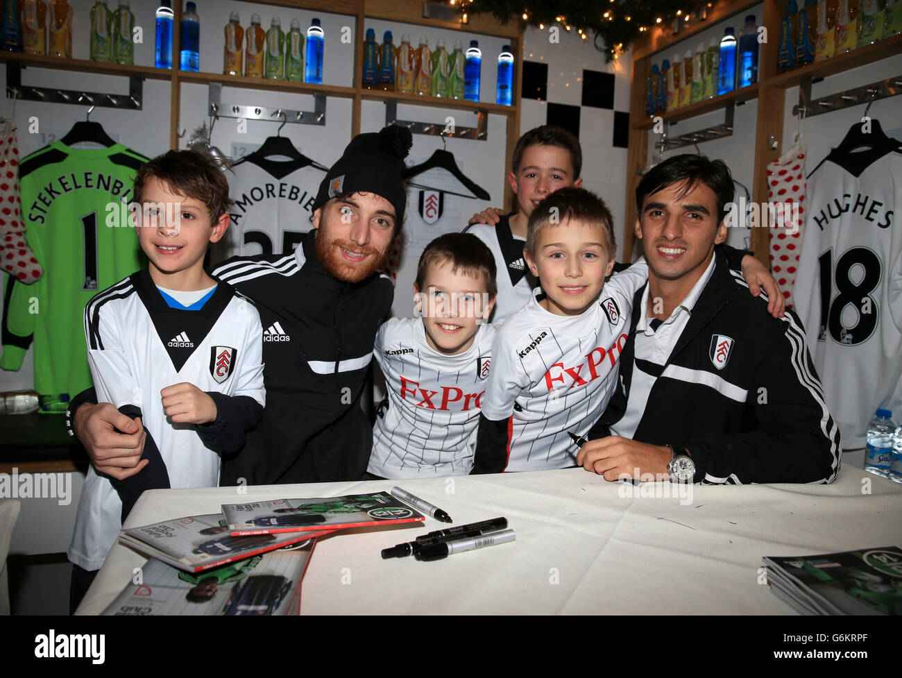 Los jóvenes fans de Fulham posan para una foto con Bryan Ruiz y Fernando Amorebieta (izquierda) durante la Navidad en el evento Cottage Foto de stock