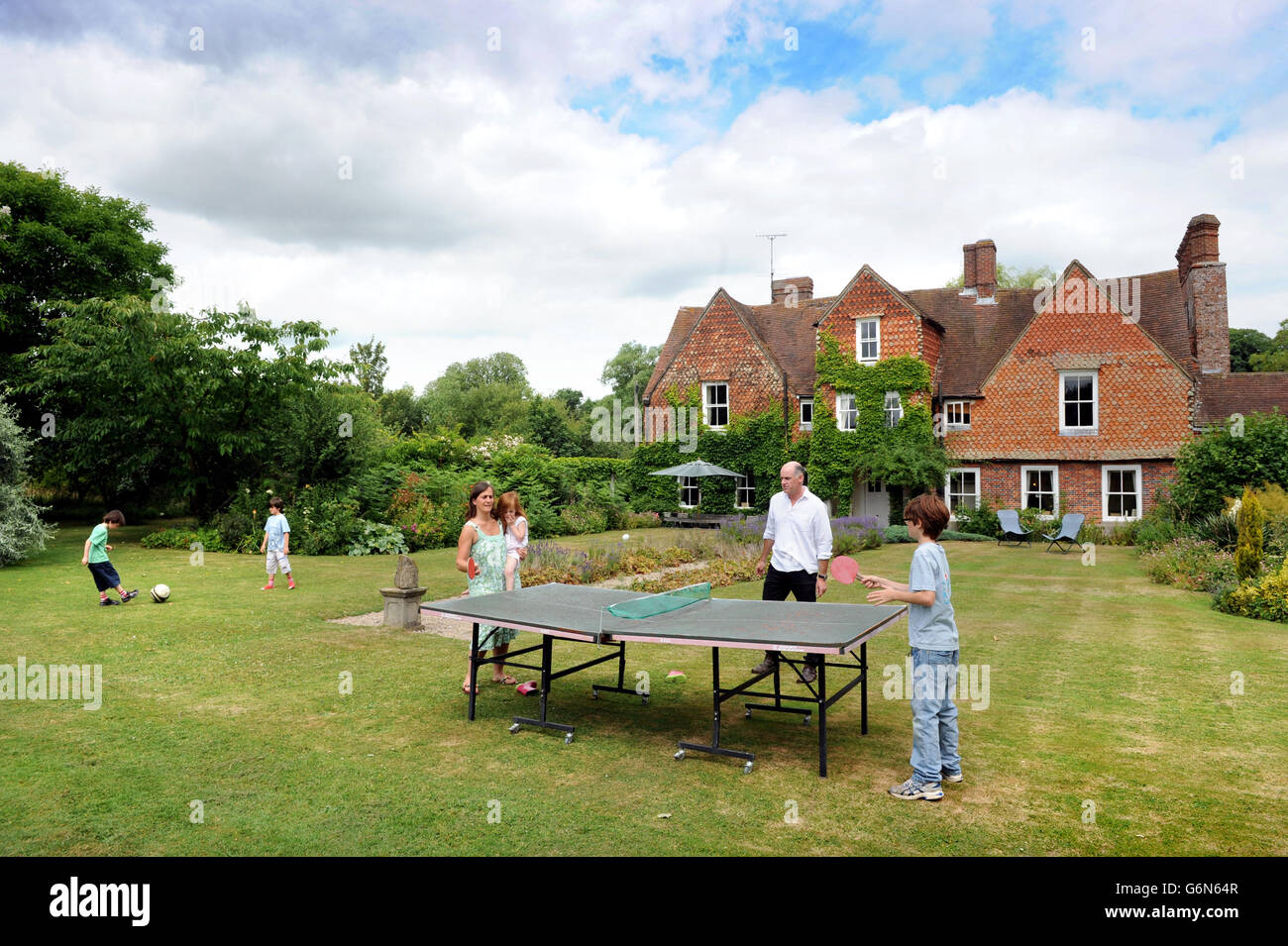 Una familia jugando al tenis de mesa en el jardín UK Foto de stock