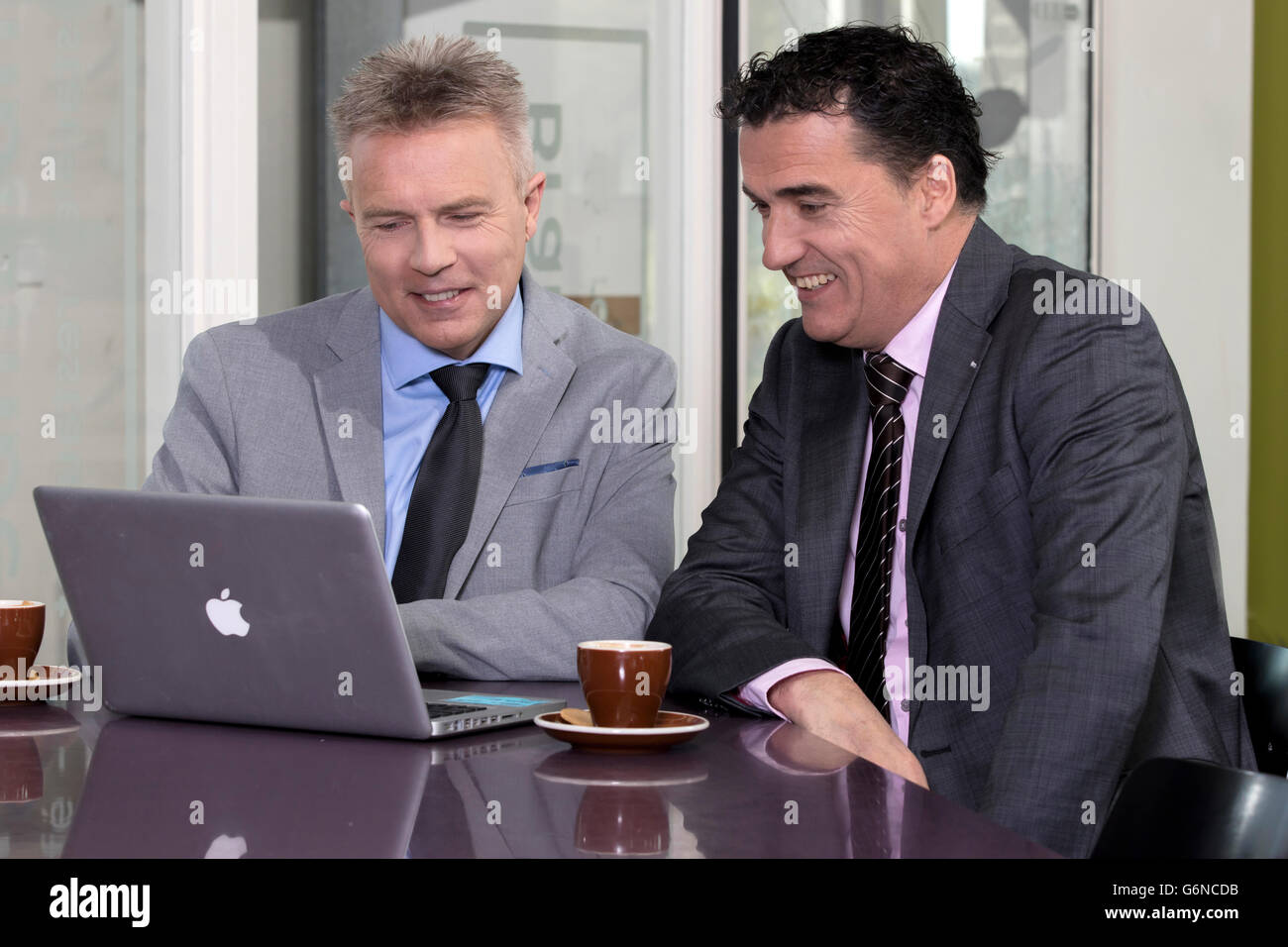 Seguros y socios de negocios exitosos en la mesa detrás de laptop evaluar con una taza de café, la oficina moderna, cliente consejos Foto de stock
