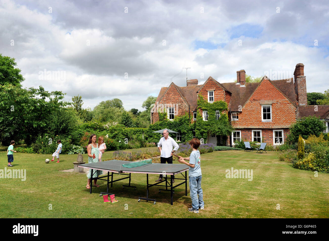 Una familia jugando al tenis de mesa en el jardín UK Foto de stock