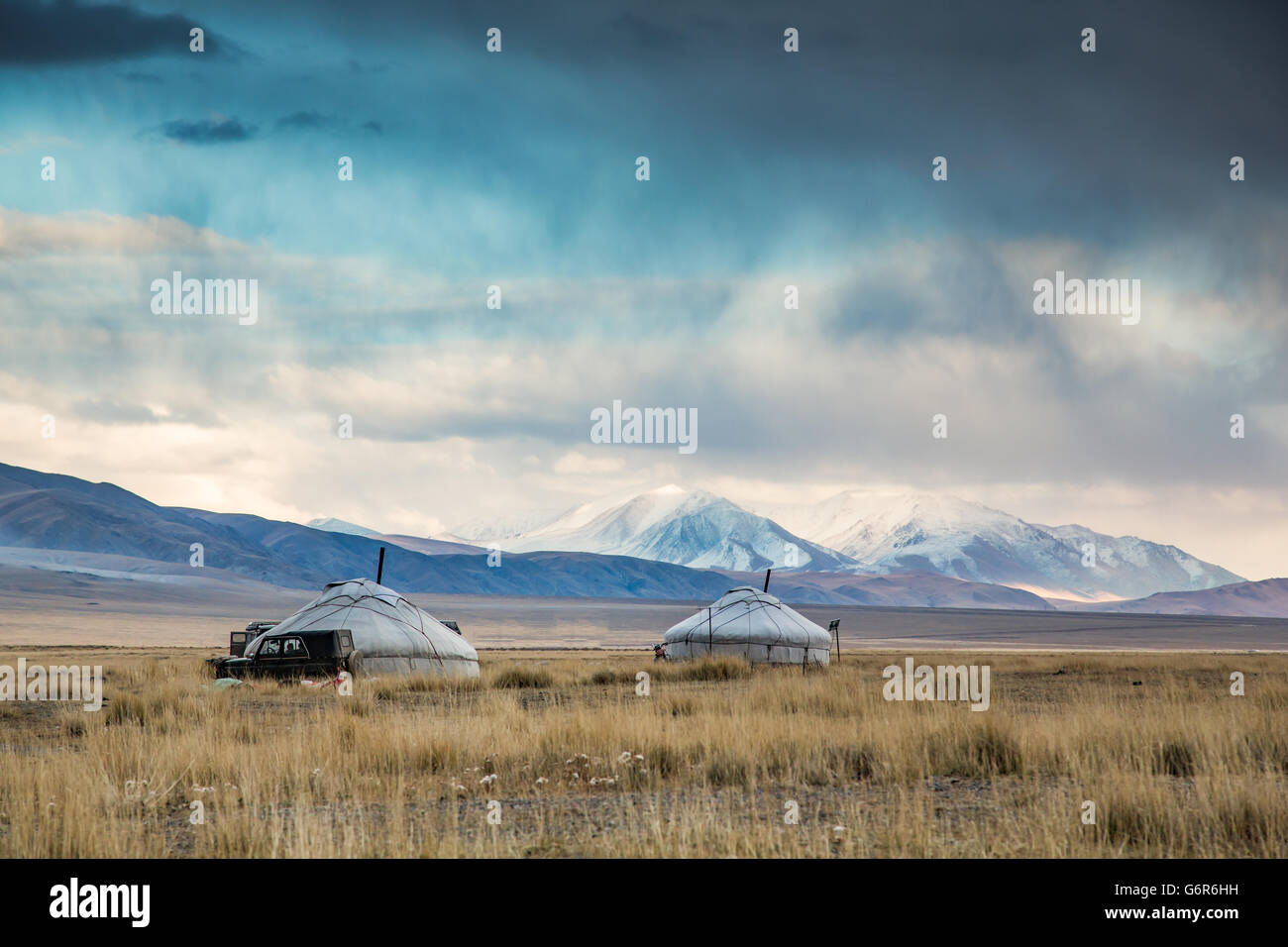 Dos yurts en un paisaje de Mongolia occidental con montañas nevadas en el fondo Foto de stock