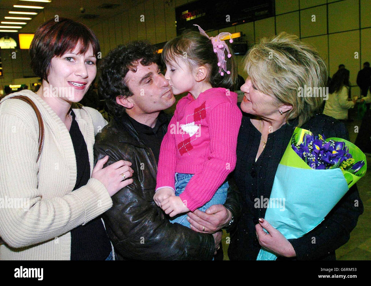 Bedri Haziri, solicitante de asilo (segunda izquierda), con su esposa Susan (R), ya que se reúnen con su nieta Molly de 5 años, y su hija Kate (extrema izquierda) cuando se reunieron en el aeropuerto de Heathrow ayer por la noche. Bedri, conocido y popular en Teignmouth, donde estaba buscando asilo después de huir de su Kosovo natal debido a la violencia, se enamoró de una mujer local Susan Giesler, y se casaron en septiembre de 2000. Con la amenaza de deportación que se cierne sobre la pareja, Bedri fue deportado a Albania el pasado diciembre, pero desde entonces ha recibido una visa de cónyuge para reunirse con su familia en el Reino Unido. Foto de stock