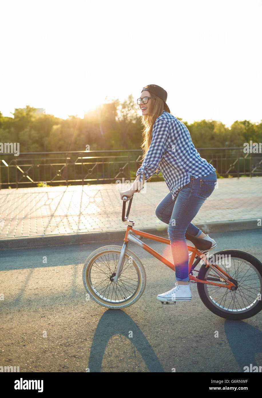 Encantadora mujer joven en un sombrero a montar una bicicleta en la ciudad en el fondo la luz solar exterior. Las personas activas Foto de stock