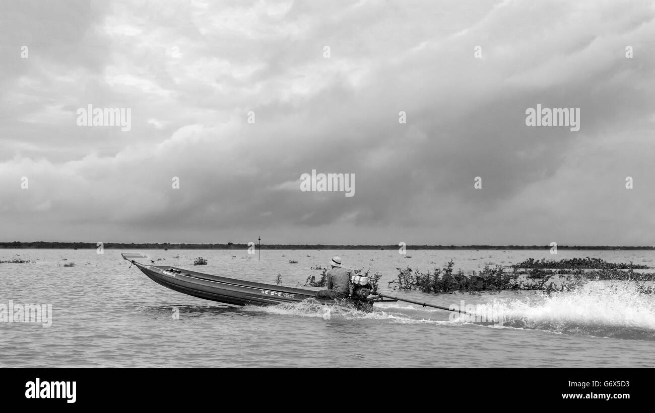 Long tail boat acelerando a través de Tonle Sap con nubes en el horizonte, Camboya Foto de stock