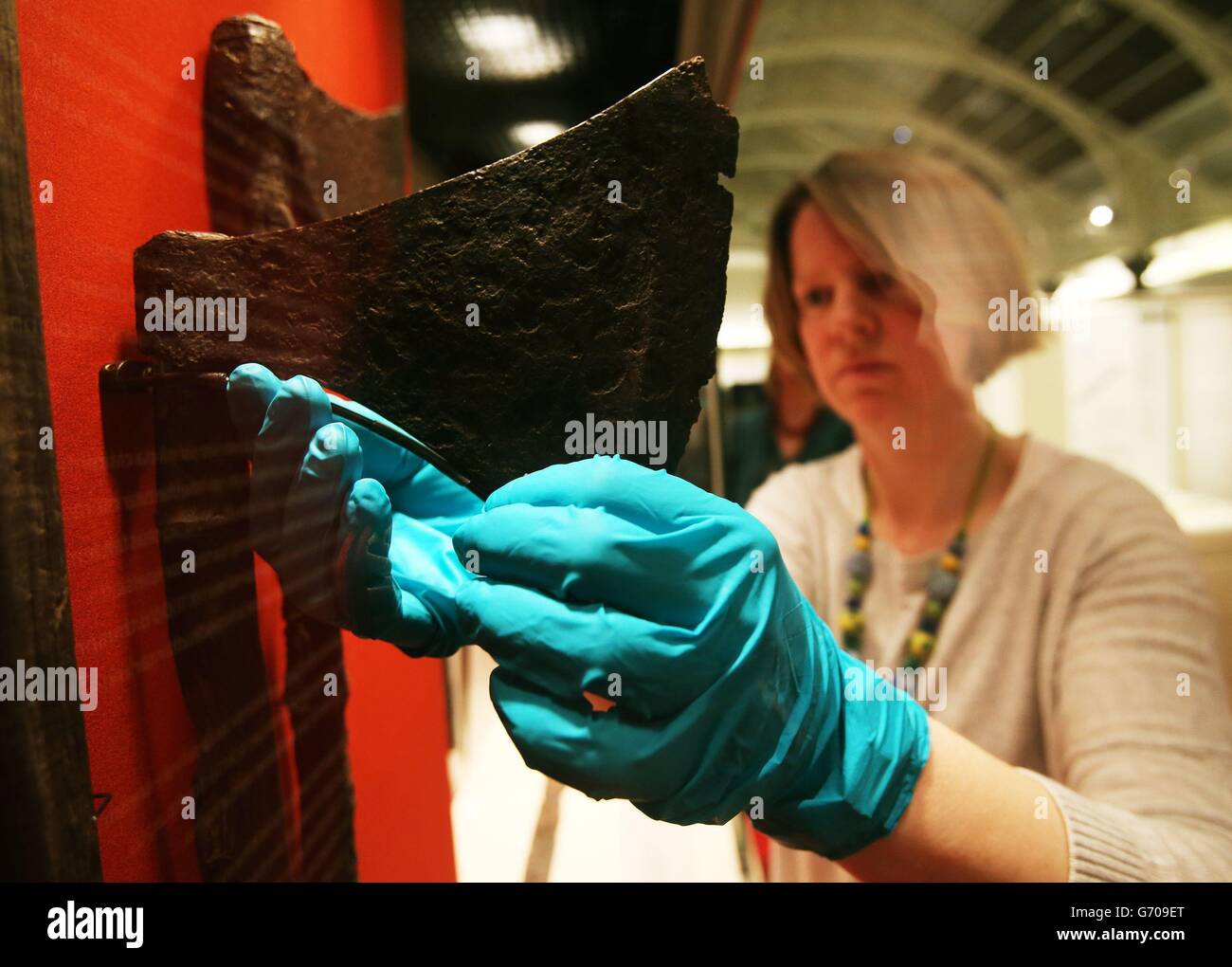 La conservadora Carol Smith hace ajustes a los hachas vikingos que fueron encontrados en Lough Corrib en 2013, en el lanzamiento de dos exposiciones, en el Museo Nacional de Irlanda, Dublín, para conmemorar el 1000th aniversario de la Batalla de Clontarf. Foto de stock