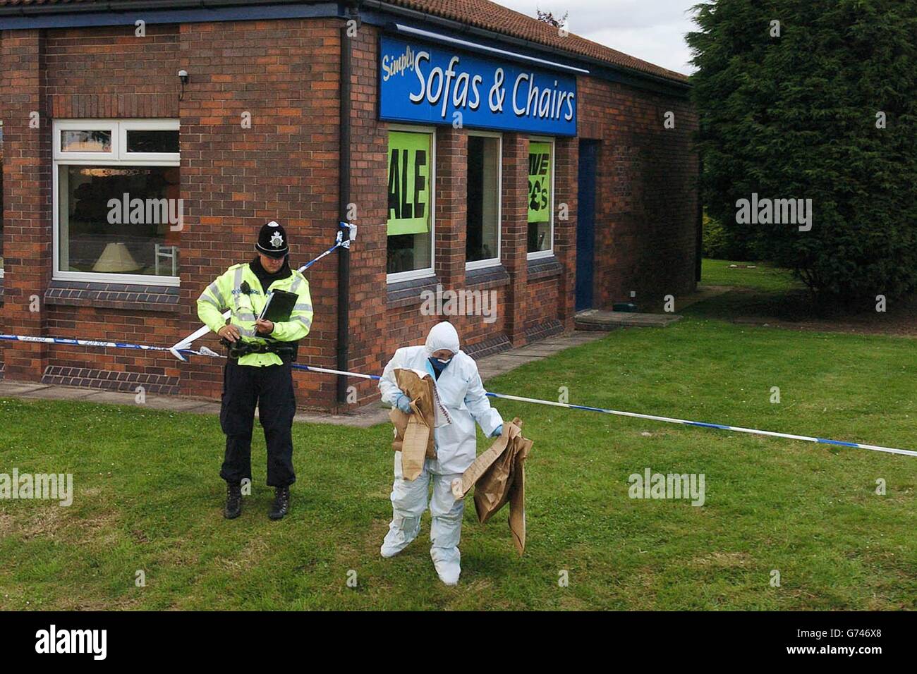 Un agente forense de la policía retira pruebas de arbustos detrás de la