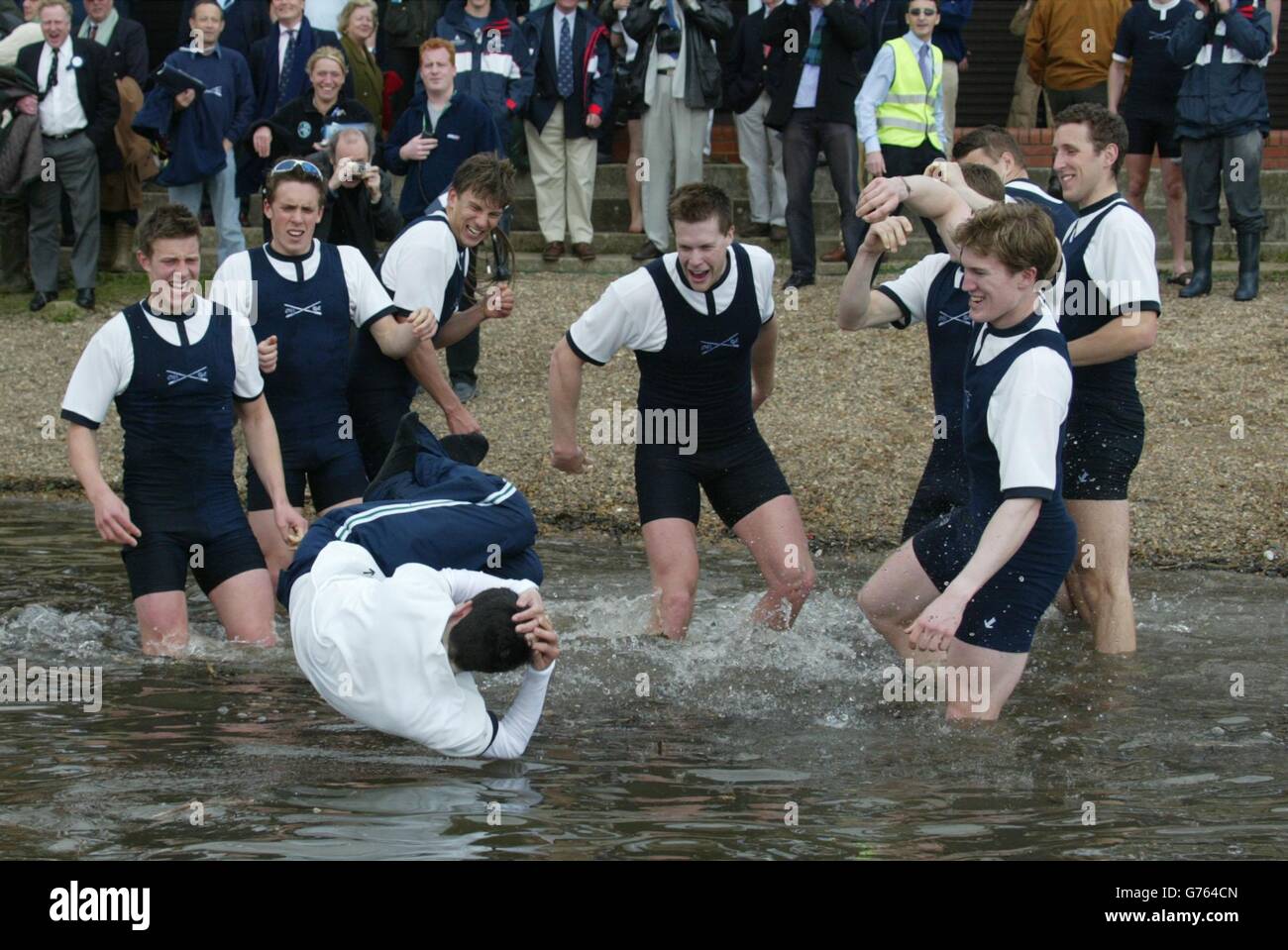 Oxford cox Peter E P Hackworth se adentra en el agua mientras su tripulación celebra una estrecha victoria sobre Cambridge en la carrera de botes universitarios de 148th en el Támesis. Foto de stock